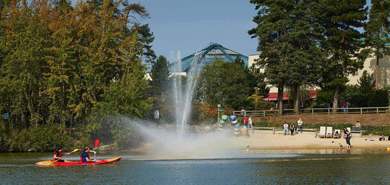 Beach and lake at elveden with water fountain and two men on a canoe