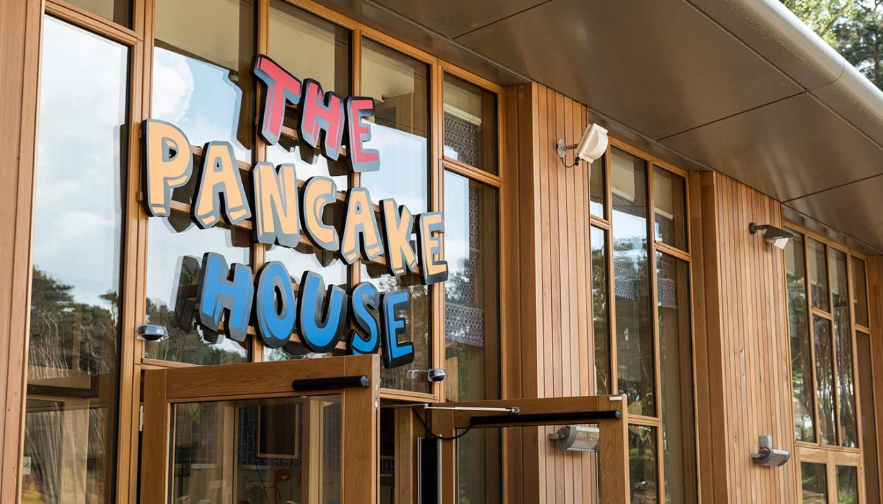 The exterior of the Pancake House- a wooden building with the Pancake House logo on it 