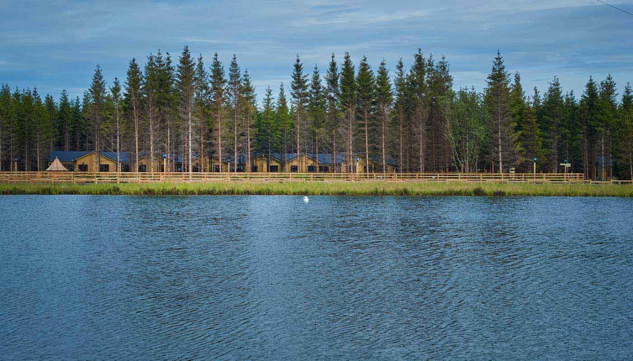 View of lake with forest and lodges in the distance