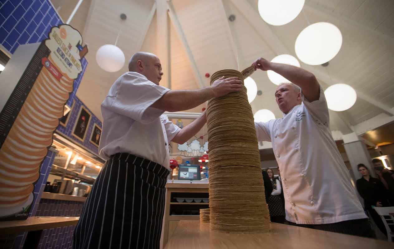 Two staff members making the highest stack of pancakes to beat the Guinness World Record