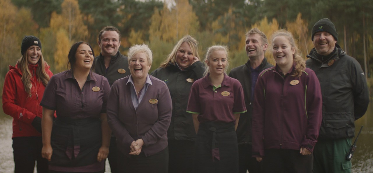 Members of staff from different departments on village smiling and laughing at the camera