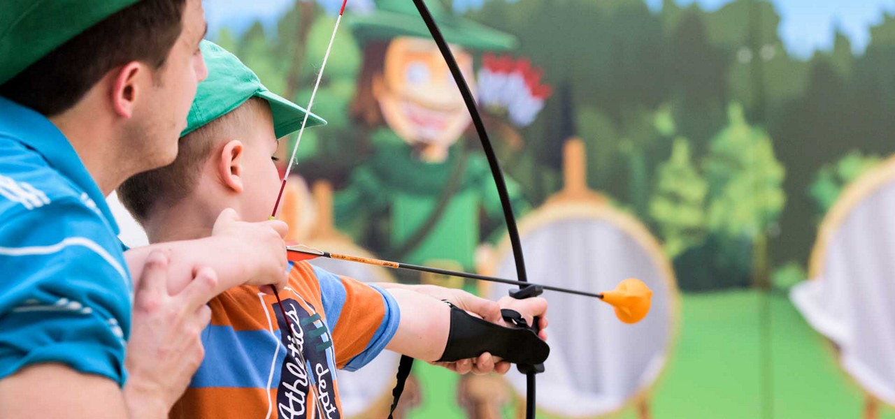 Father and son holding a bow and arrow ready to shoot at the target