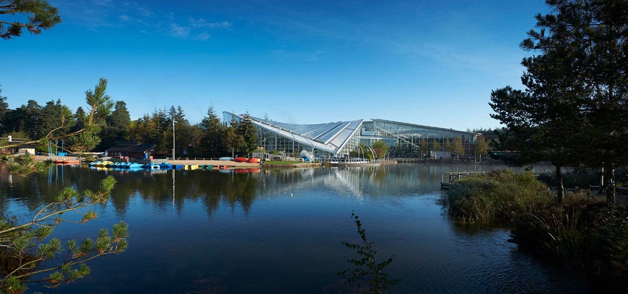 Exterior view of Subtropical Swimming Paradise with lake in front of it at Whinfell Forest