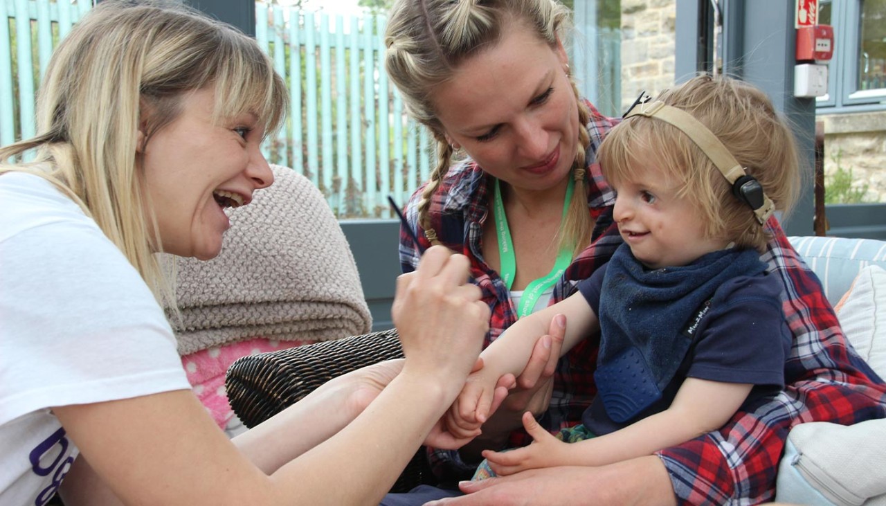 A child with a hearing impairment playing with two adult volunteers