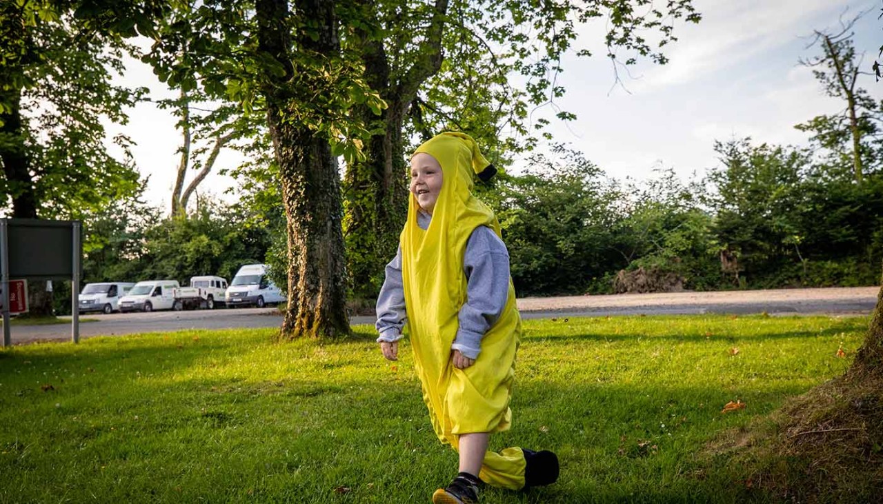 Child in banana outfit running across grass