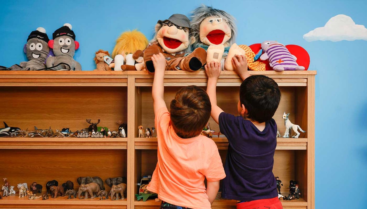 Two young boys reaching for toys on a shelf