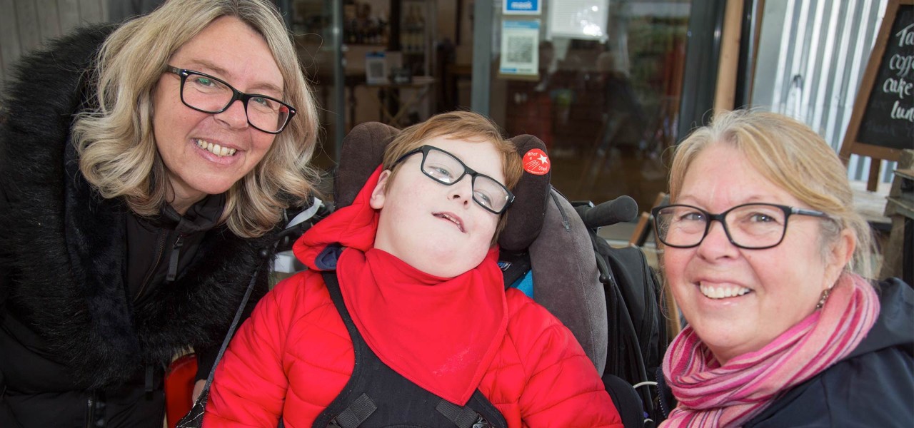 Two women and a disabled child smiling at camera