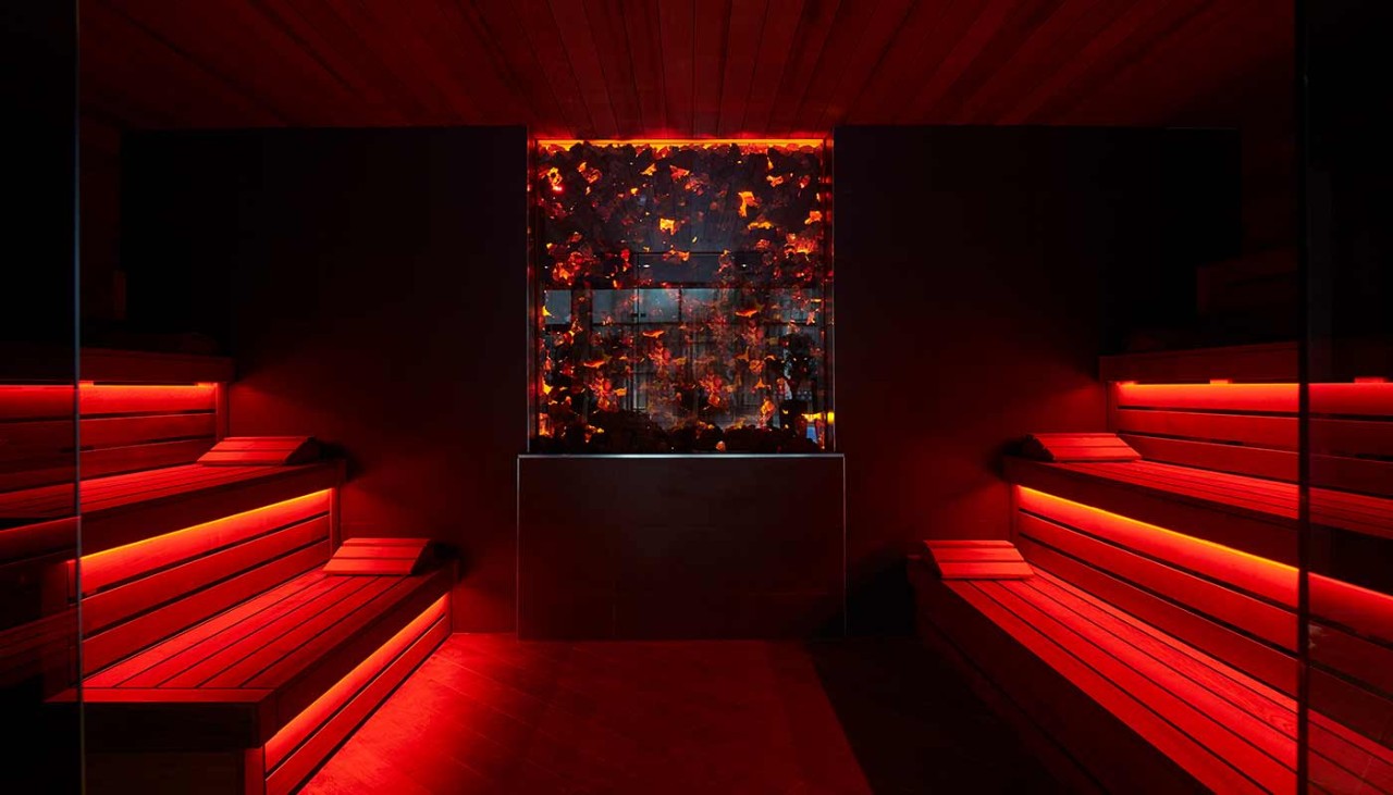 Inside lava sauna with red lights shining through the seating area